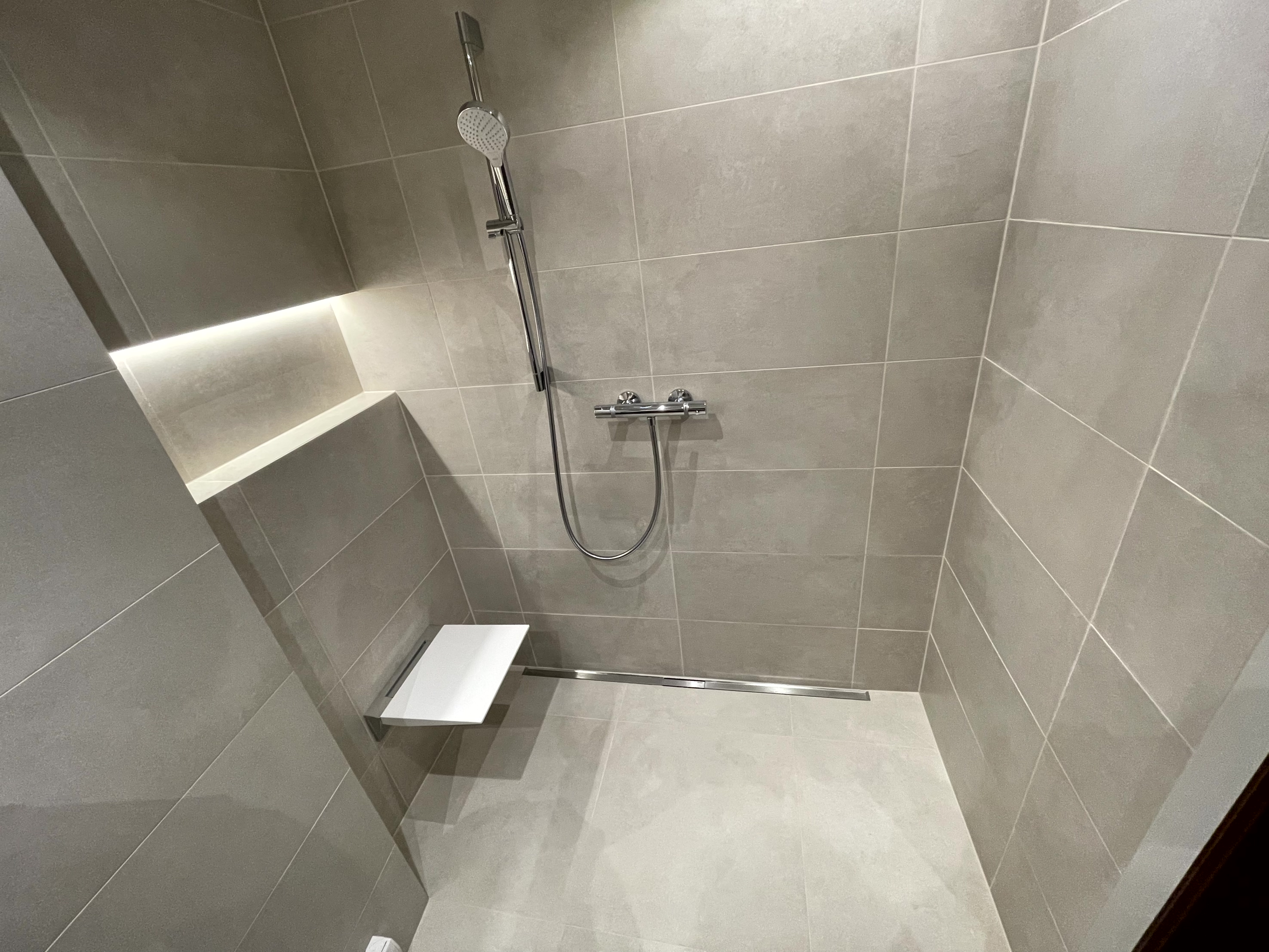 Moderne Badsanierung Wien — ebenerdige Dusche mit beleuchteter Wandnische von Holtex